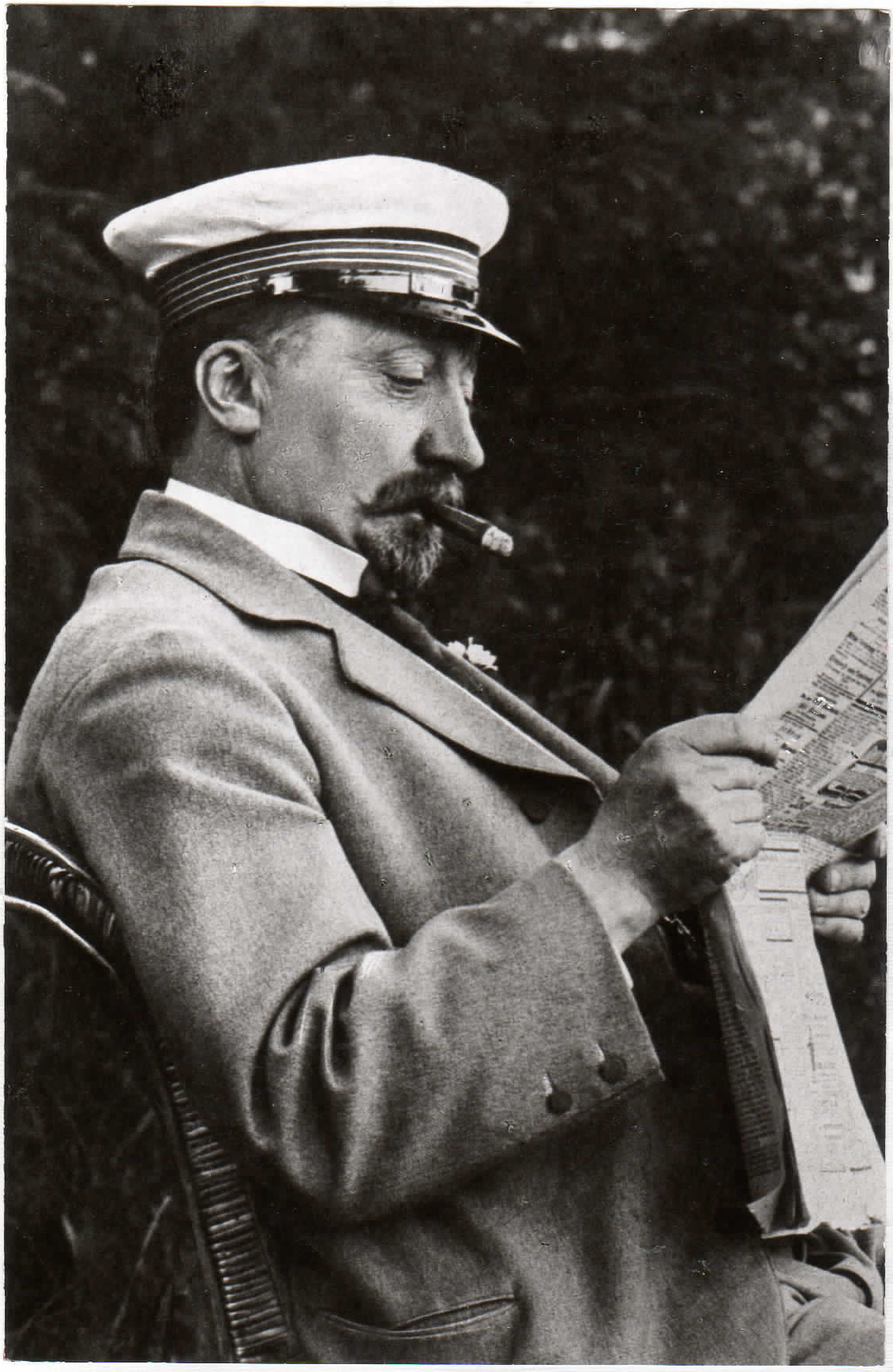 Conrad Bauscher sitzt mit Schirmmütze und Zeitung in einem Korbstuhl.