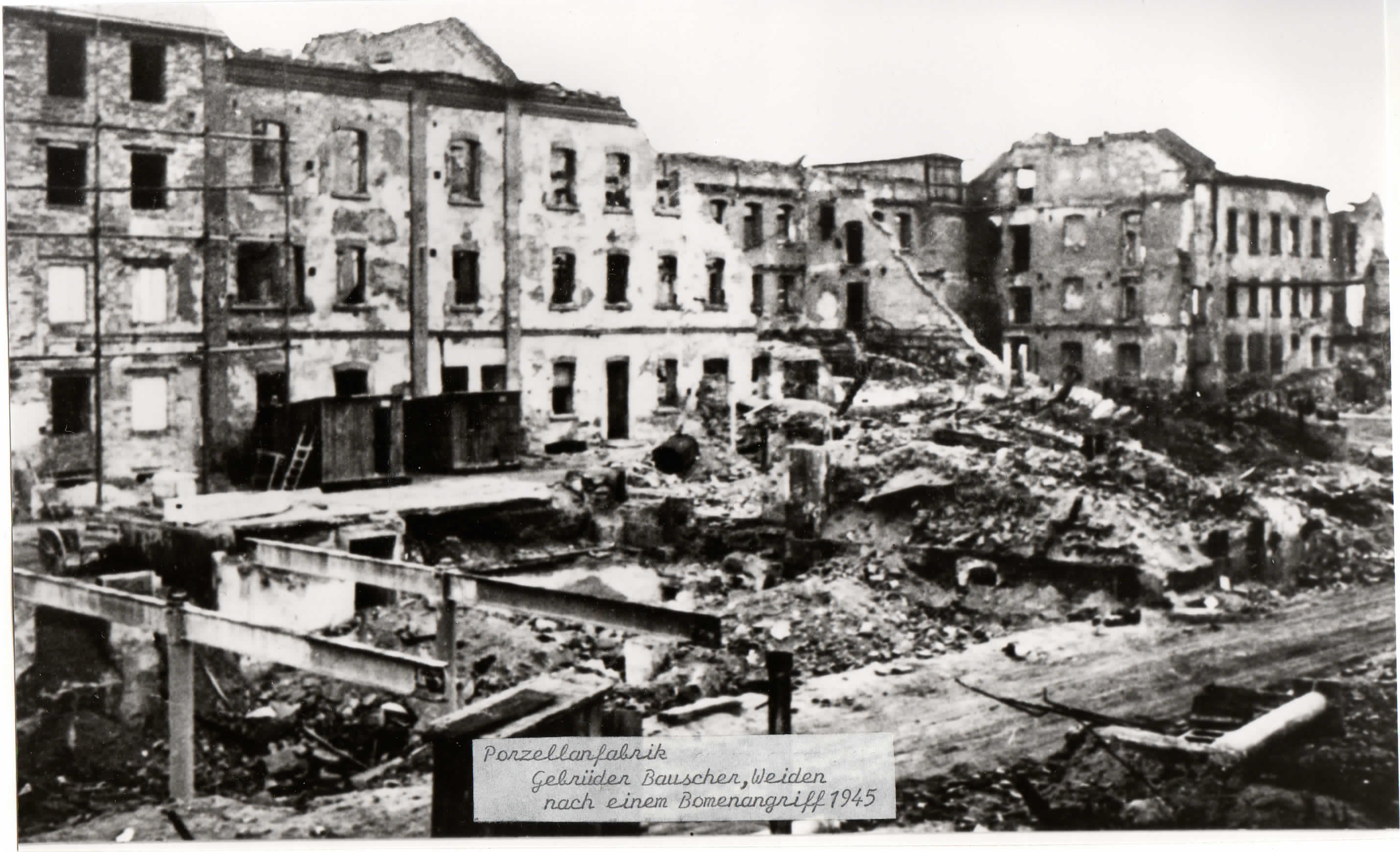 Zerstörte Fabrikgebäude, offene Fensterhöhlen und Trümmer auf dem Bauscher-Werksgelände nach einem Bombenangriff 1945.