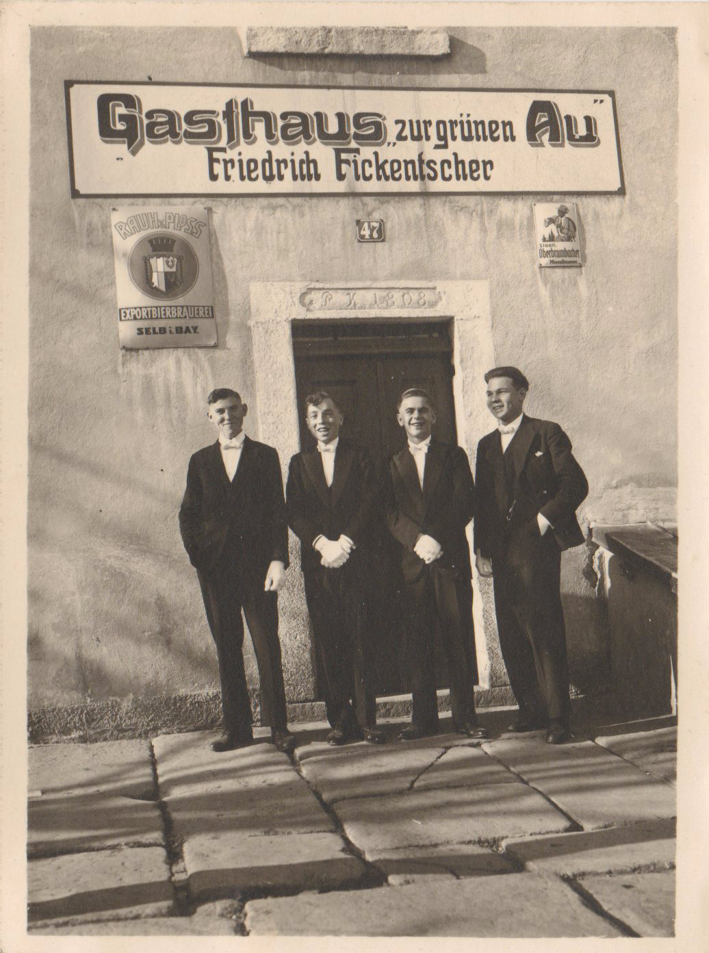 Vier Männer stehen auf der Eingangstreppe unter dem Schild Gasthaus zur grünen Au, Friedrich Fickenscher.