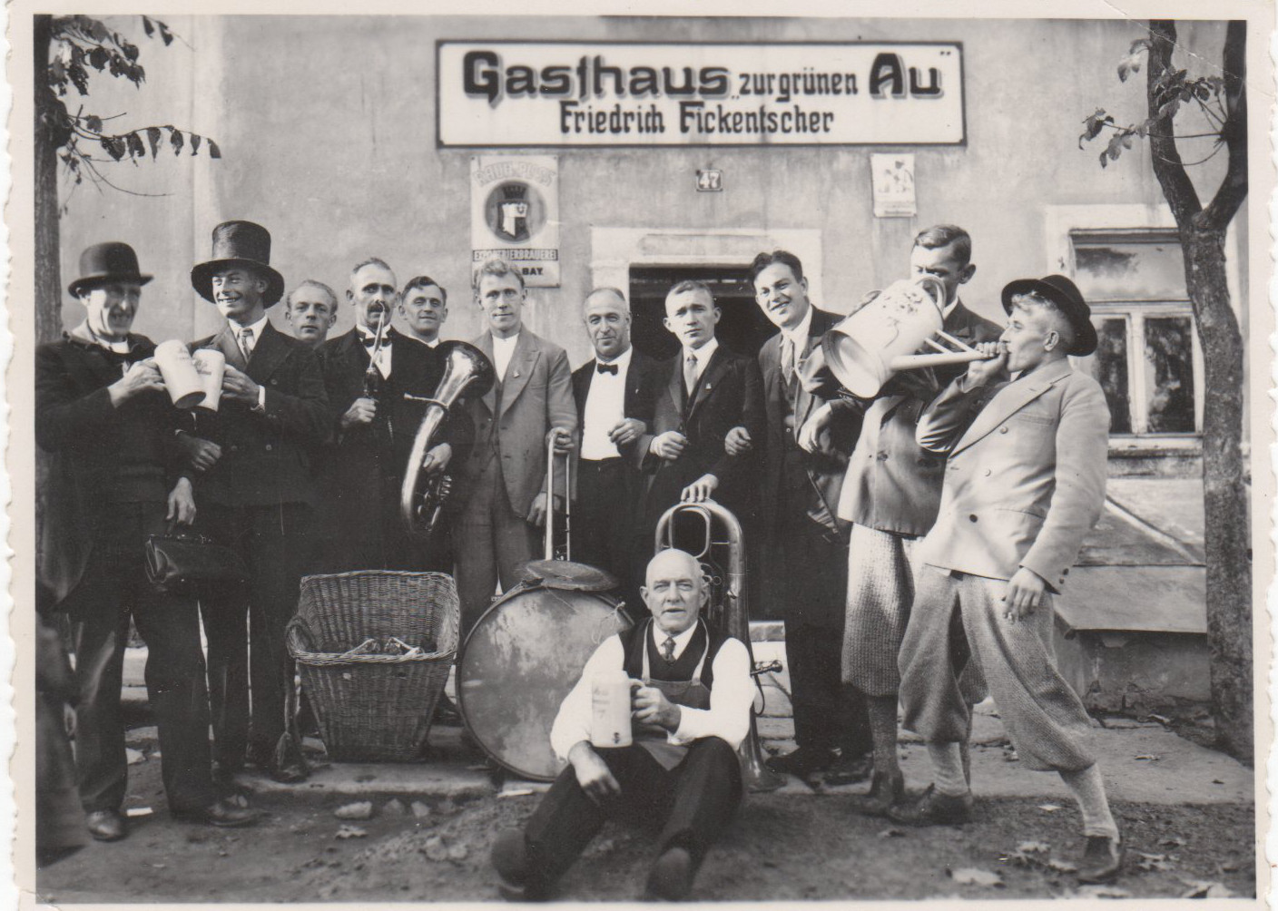 Gruppe mit Instrumenten, Trommel, Korb und Kanne vor dem Eingang der Grünen Au.