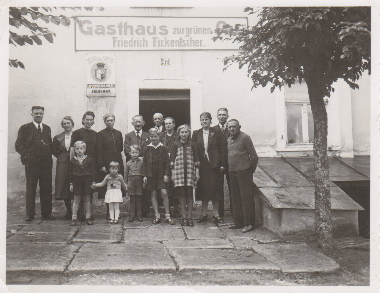 Erwachsene und Kinder stehen gemeinsam vor dem Eingang des Gasthauses Zur grünen Au.