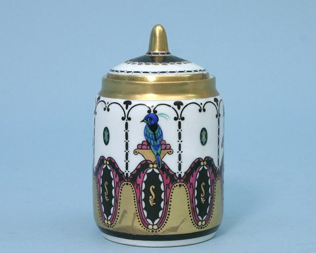 Zylindrische Porzellandose mit Deckel, goldfarbenem Knauf und farbigem Vogel- und Pflanzenornament vor blauem Hintergrund.
