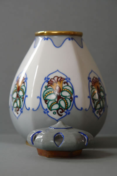 Bauchiges weißes Porzellangefäß auf kurzem Fuß mit bunten Blütenmedaillons und blau-goldenen Randornamenten.
