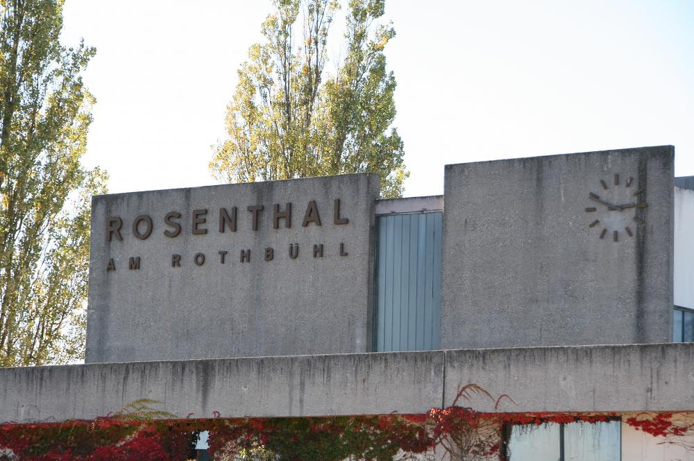 Schriftzug Rosenthal am Rothbühl an einer Betonfassade, daneben eine Uhr.
