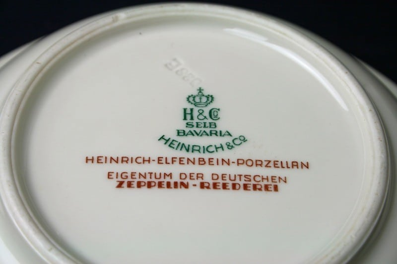 Tellerunterseite mit grüner Heinrich-Herstellerkennzeichnung und rotem Aufdruck Heinrich-Elfenbein-Porzellan Eigentum der Deutschen Zeppelin-Reederei.