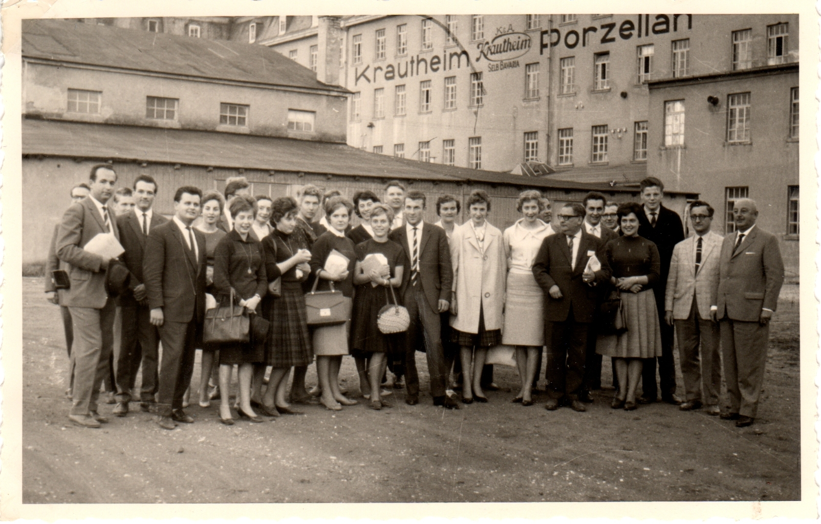 Eine größere Gruppe von Frauen und Männern steht vor dem Fabrikgebäude mit dem Schriftzug Krautheim Porzellan.