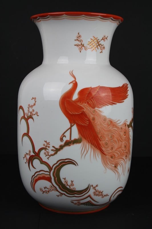 Weiße Vase mit rotem Vogel, feinen Ranken und farbigem Rand.