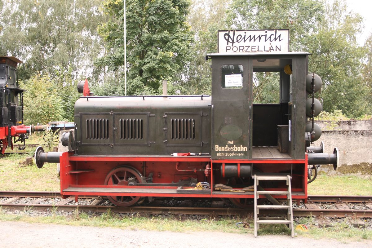 Kleine schwarze Diesellokomotive mit rotem Fahrwerk und Schild Heinrich Porzellan.