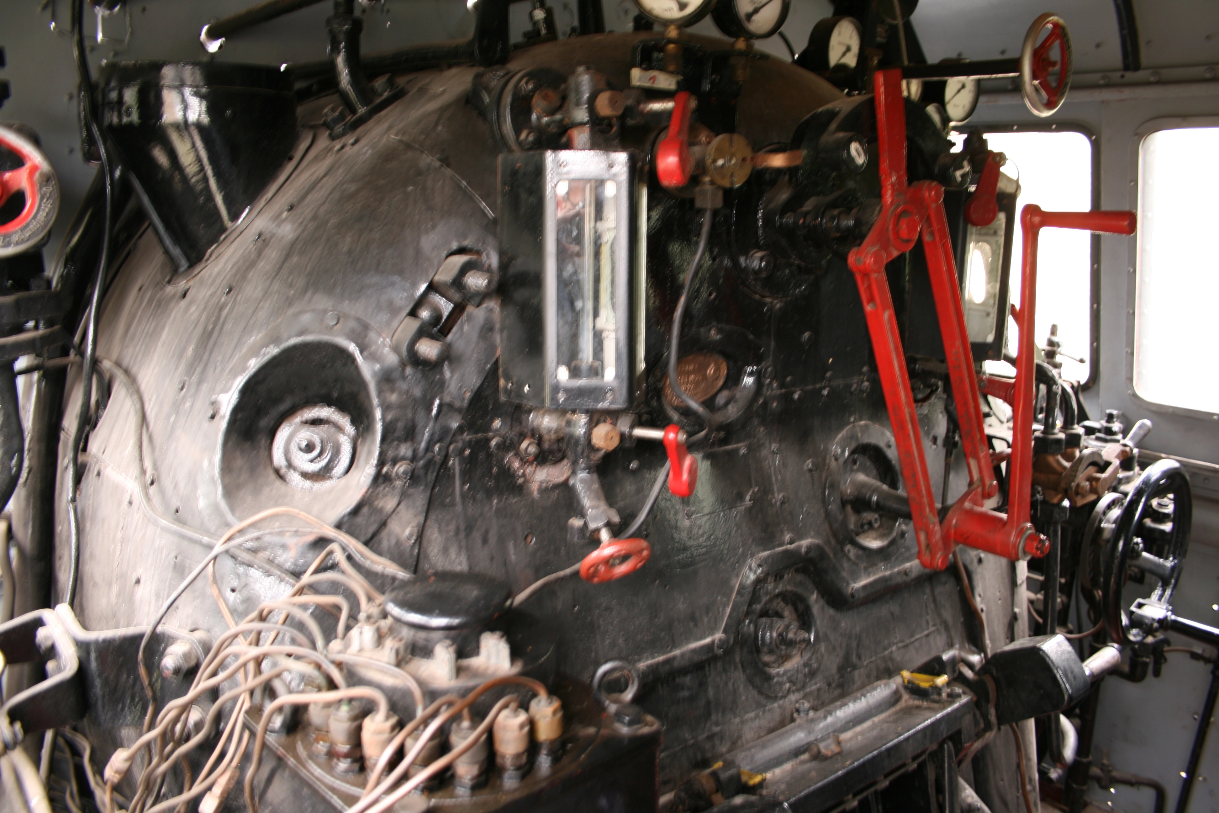 Armaturen, Hebel und Feuerungsbereich im Führerstand einer Dampflokomotive.