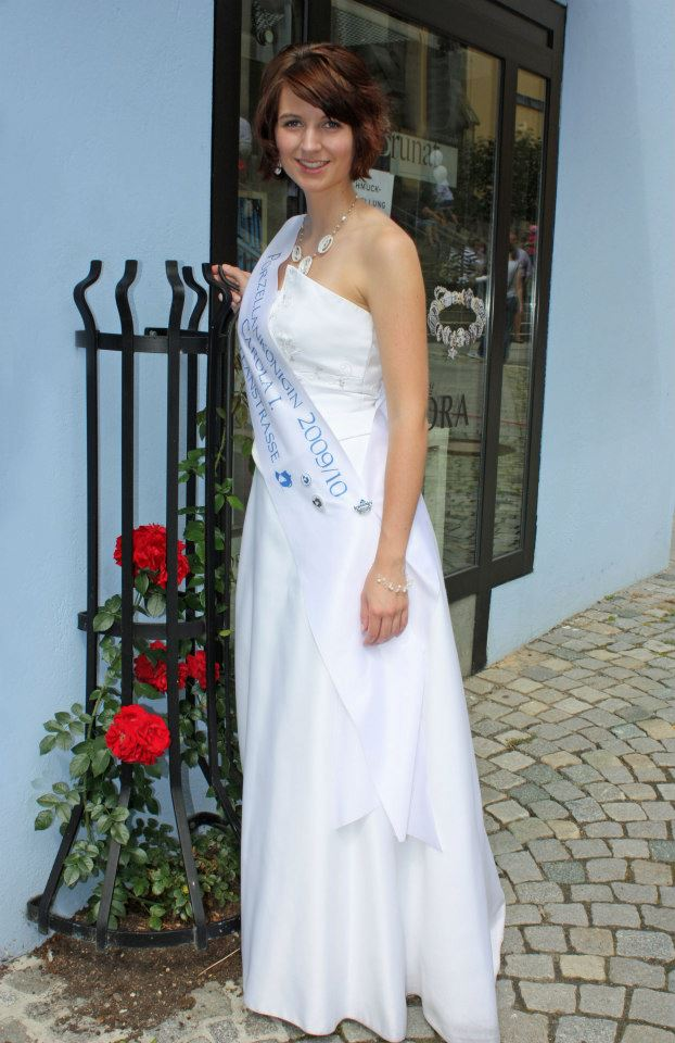 Ganzaufnahme einer festlich gekleideten Frau mit einer Schärpe der Porzellanstraße und der lesbaren Jahresangabe 2009/10.