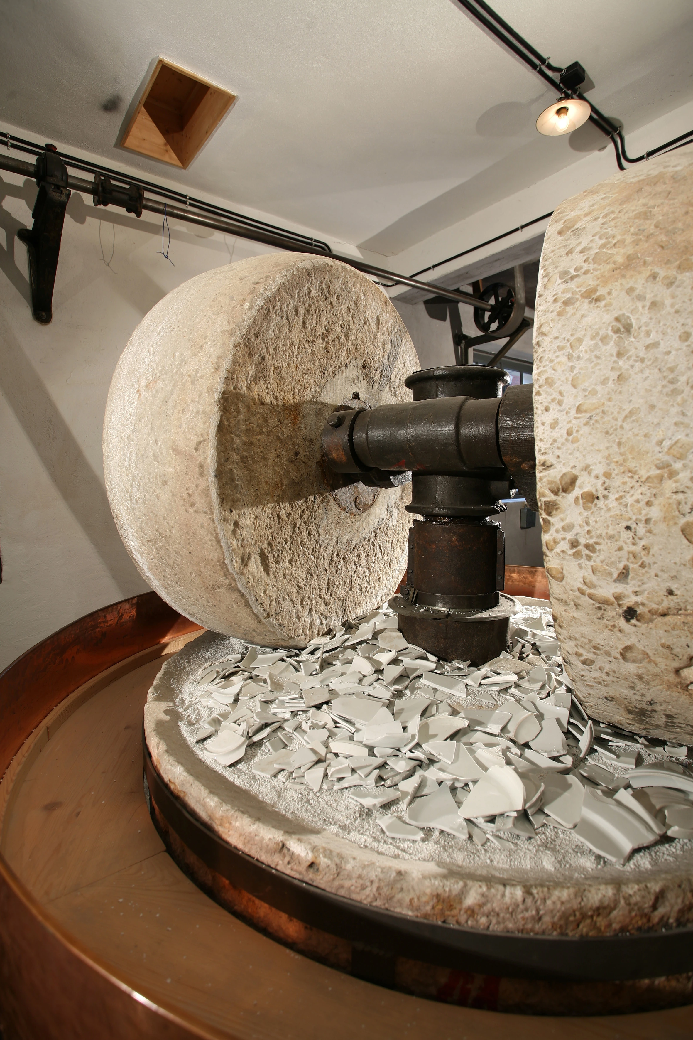 Kollergang mit schweren Mahlsteinen und Materialbett.