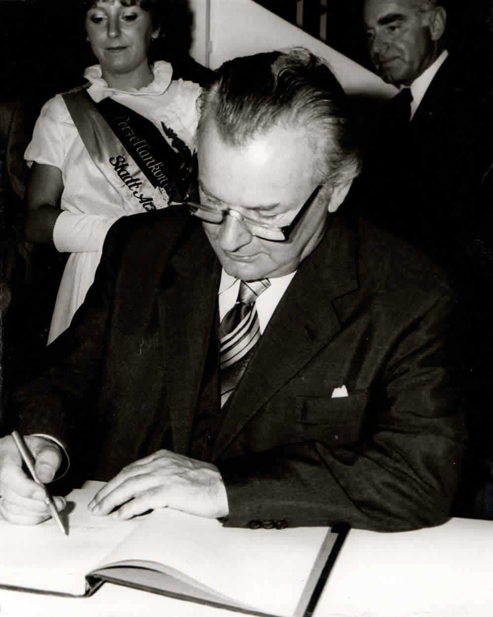 Anton Jaumann trägt sich ins Goldene Buch von Hohenberg ein; im Hintergrund die Porzellankönigin und Roland Dorschner.