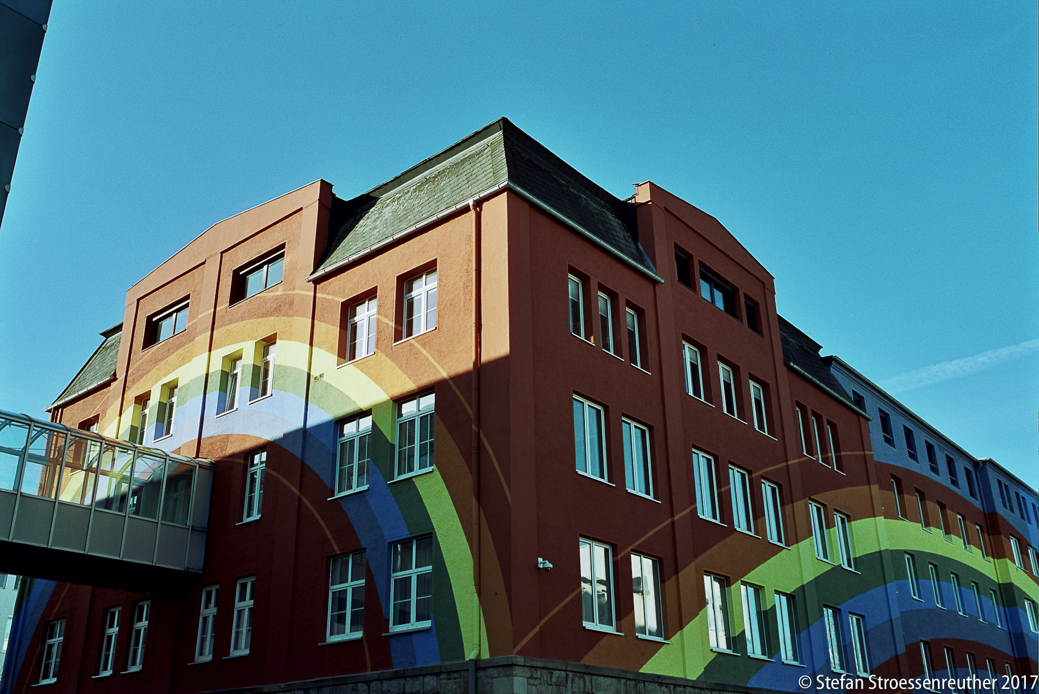 Rosenthals Regenbogenhaus in Selb: farbige Bänder ziehen über die rote Fassade und um die Gebäudeecke.