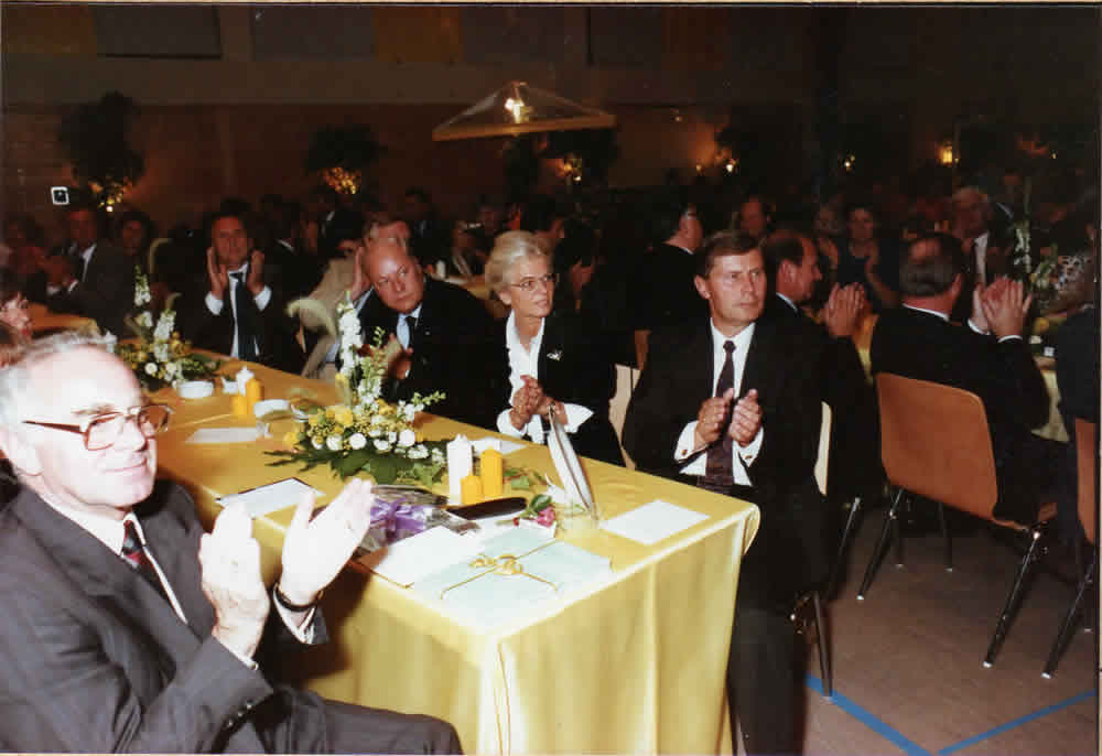 Gäste sitzen an gedeckten Tischen in einem Festsaal.