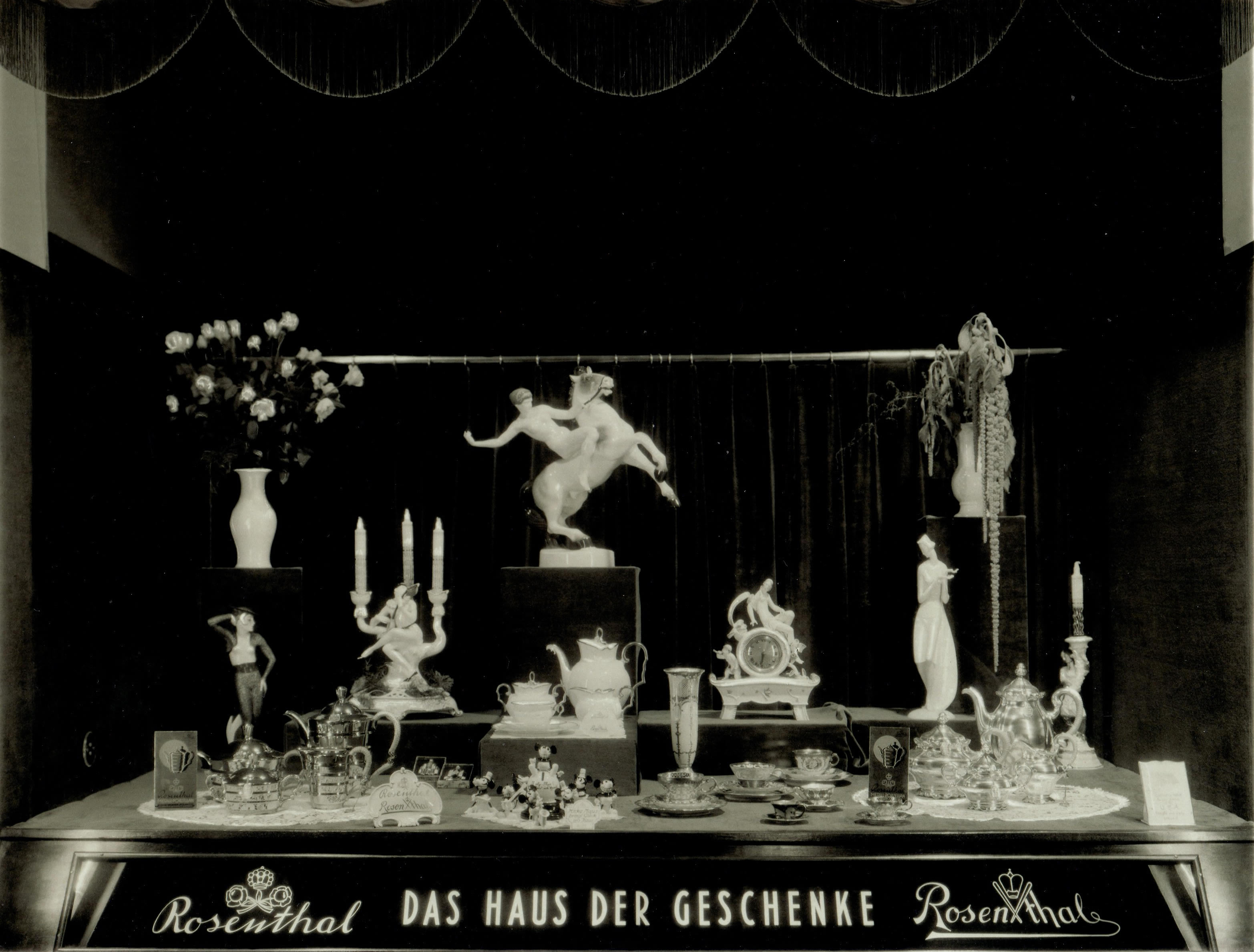 Historisches Rosenthal-Schaufenster mit Figuren, Kerzenleuchtern, Vasen und Geschirr sowie dem Schriftzug Das Haus der Geschenke.
