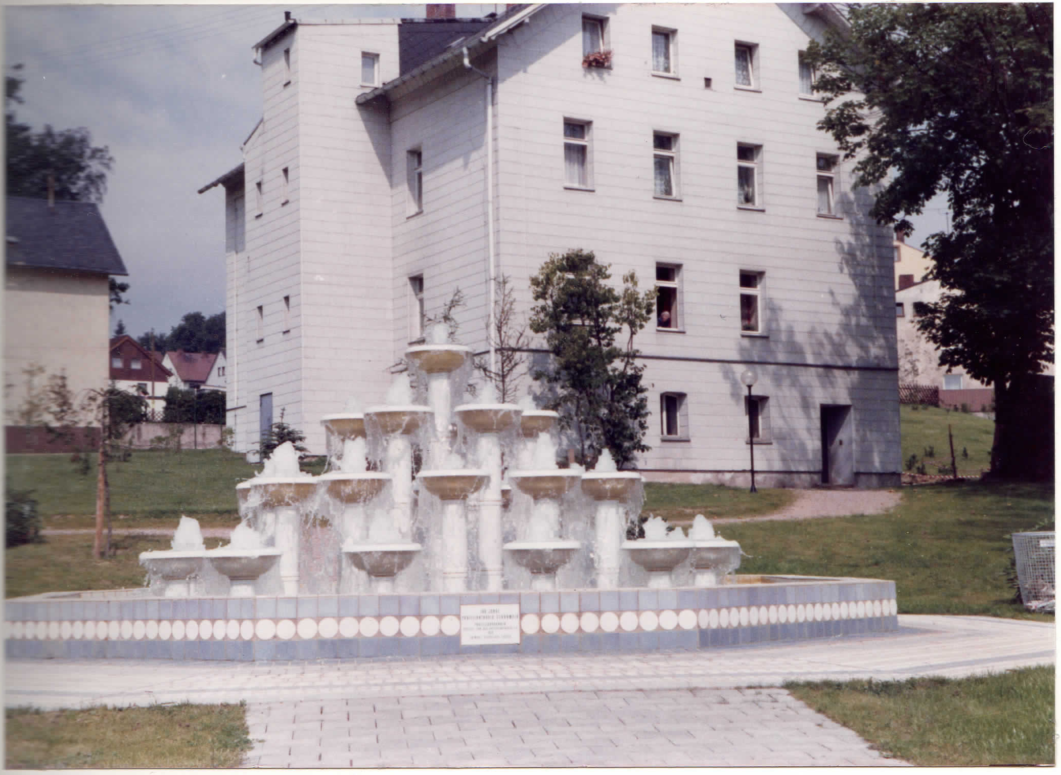 Gestufter Porzellanbrunnen mit Wasserspielen vor einem mehrgeschossigen Gebäude in Schönwald.