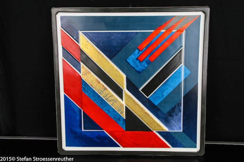 Quadratischer Porzellanteller mit geometrischen roten, blauen, gelben, schwarzen und weißen Flächen.