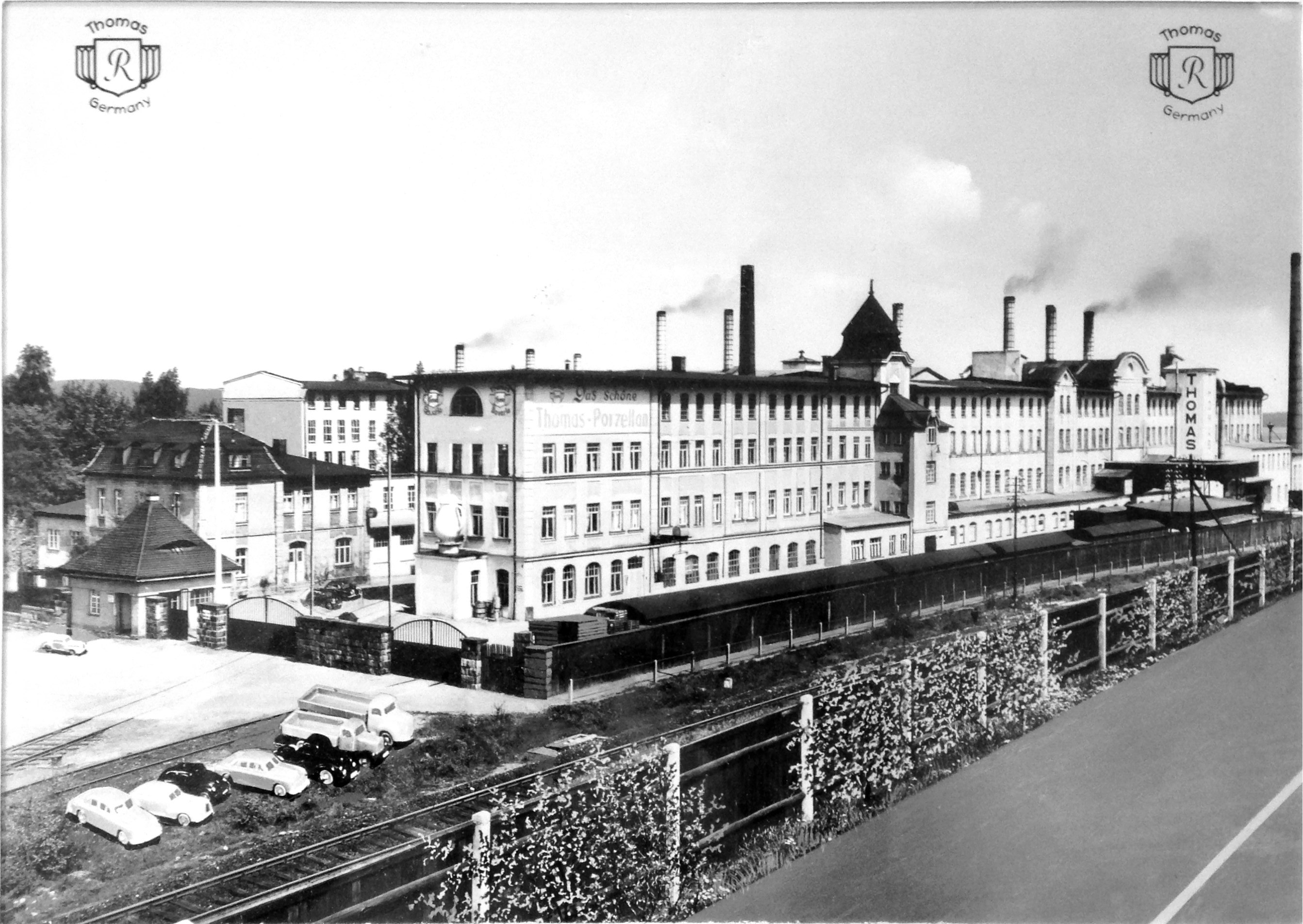 Historische Gesamtansicht der Thomas-Porzellanfabrik in Marktredwitz mit Schornsteinen, Bahnanschluss und Thomas-Markenzeichen.
