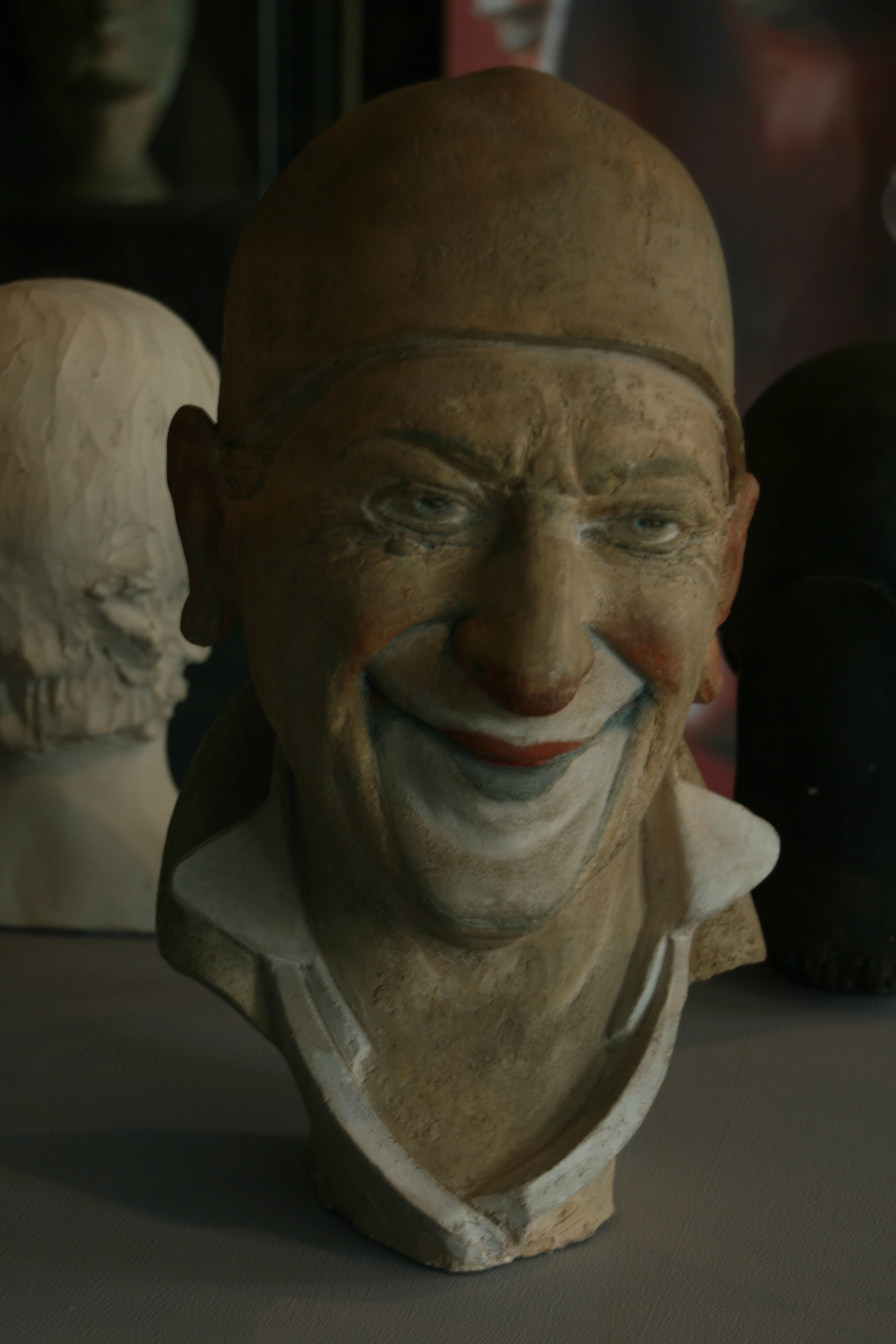 Farbig gefasstes Kopfporträt des Clowns Grock mit Kappe und geöffnetem Lächeln.