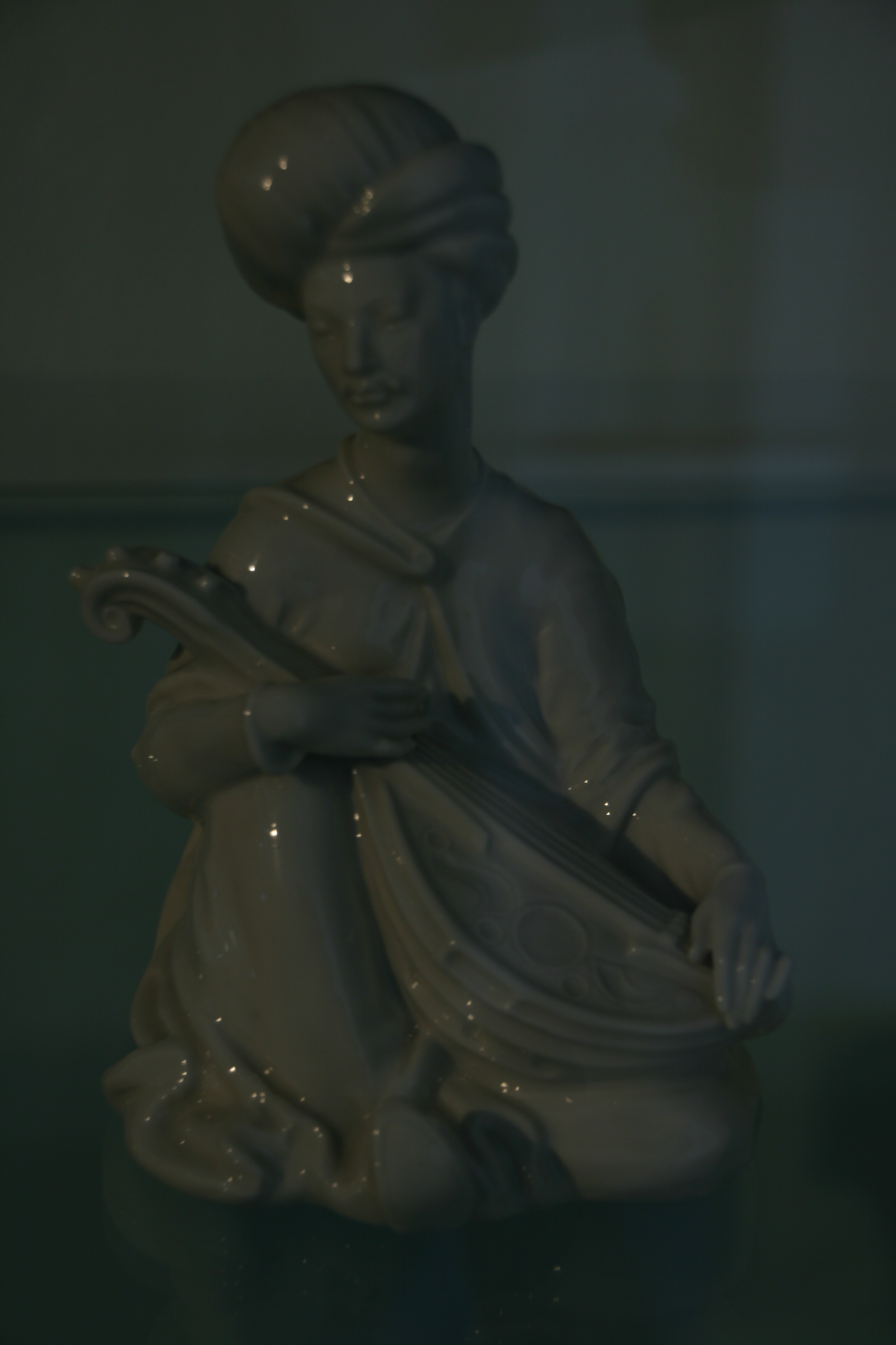 Kleine glasierte Figur eines Mädchens, das einen Fisch hält, in einer Museumsvitrine.
