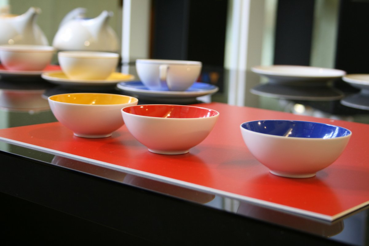 Tassen mit farbigen Innenflächen auf roter Präsentationsfläche, Ausstellung 2009.