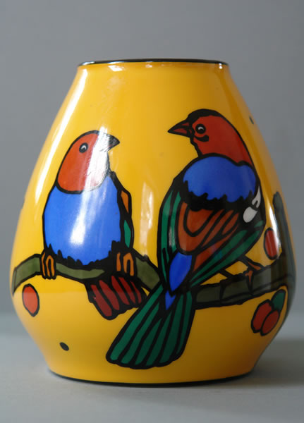 Gelbe Porzellanvase mit zwei bunt gemalten Vögeln auf Zweigen und schwarz eingefassten Farbflächen.